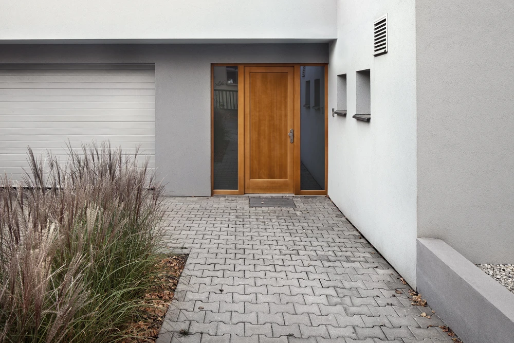 Entrée moderne de maison individuelle avec porte d'entrée en bois à panneaux encadrée de baies vitrées latérales