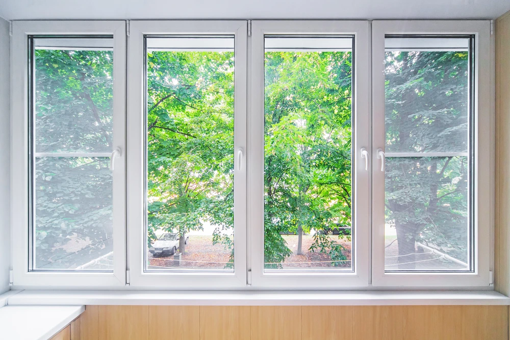 Intérieur résidentiel avec quatre fenêtres modernes à battants ouvrant sur un jardin arboré