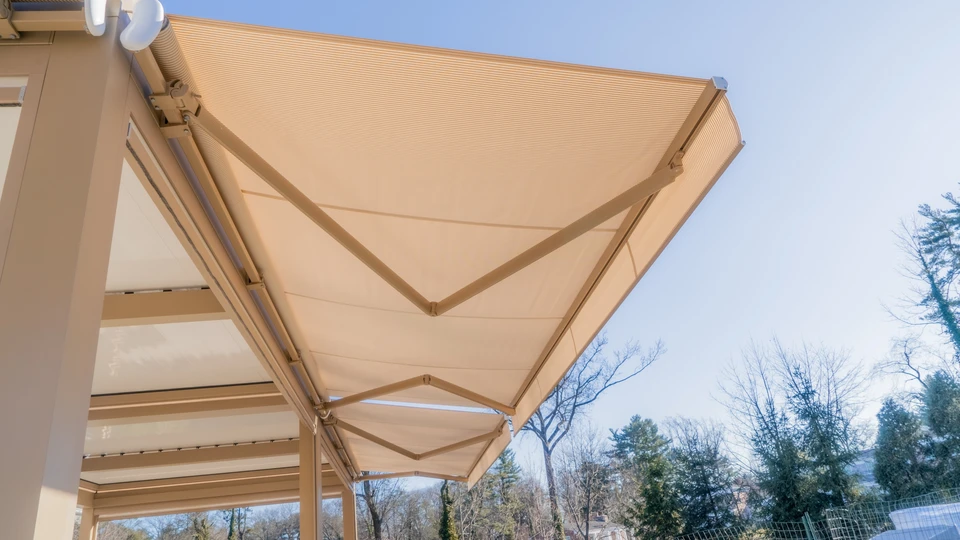 Terrasse extérieure d'une maison moderne avec store banne beige déployé créant une zone d'ombre