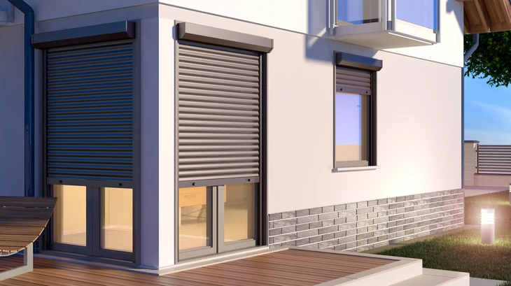 Façade moderne d'une maison contemporaine avec volets roulants métalliques, baies vitrées coulissantes et terrasse en bois