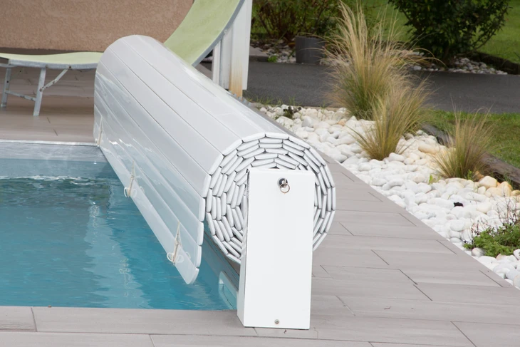 Scène extérieure de piscine résidentielle avec volet roulant automatique blanc en position semi-ouverte