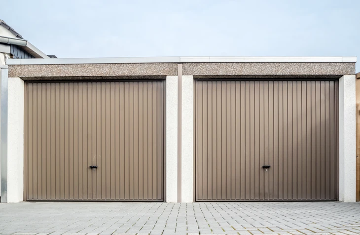 Façade extérieure de garage résidentiel avec deux portes basculantes beiges à lamelles verticales