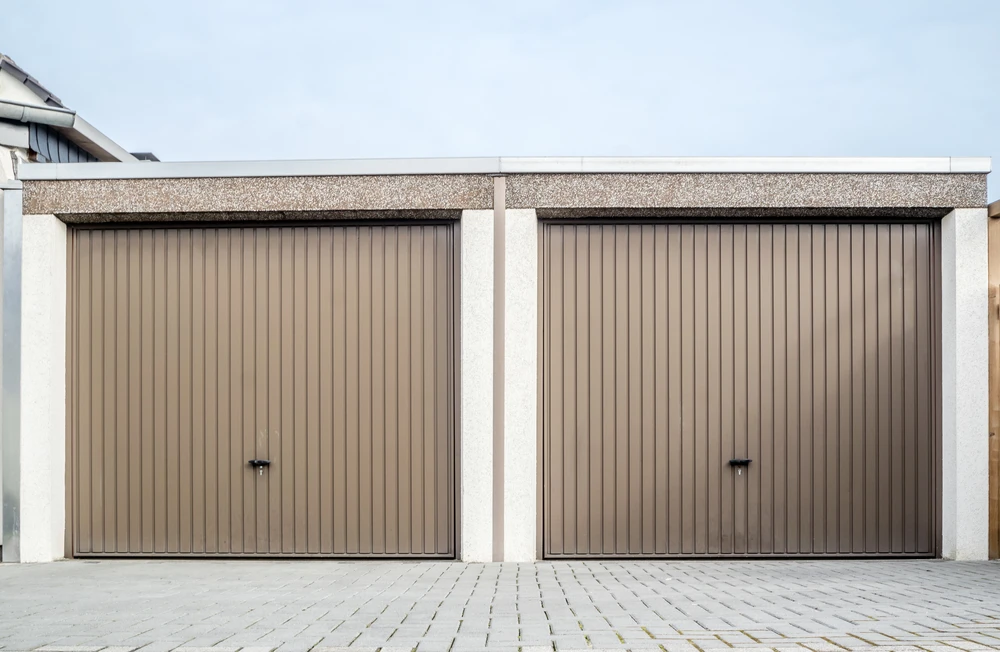 Façade extérieure de garage résidentiel avec deux portes basculantes beiges à lamelles verticales