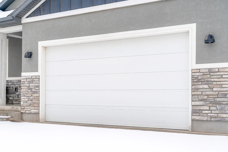 Façade résidentielle moderne avec grande porte de garage sectionnelle blanche à panneaux horizontaux