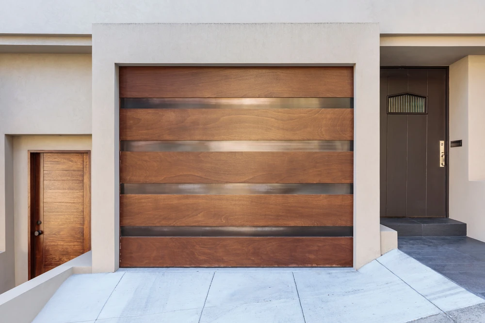 Façade extérieure moderne avec porte de garage sectionnelle en bois naturel et inserts métalliques horizontaux