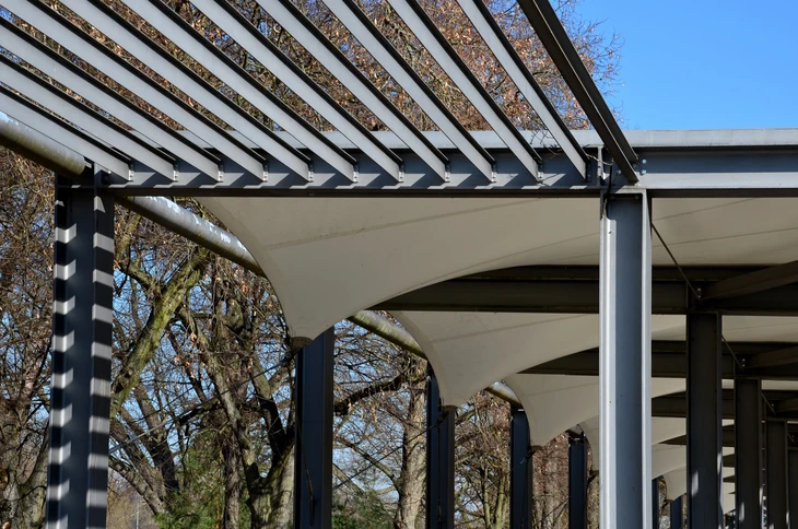 Extérieur jour, pergola moderne avec structure métallique grise et toile d'ombrage beige tendue