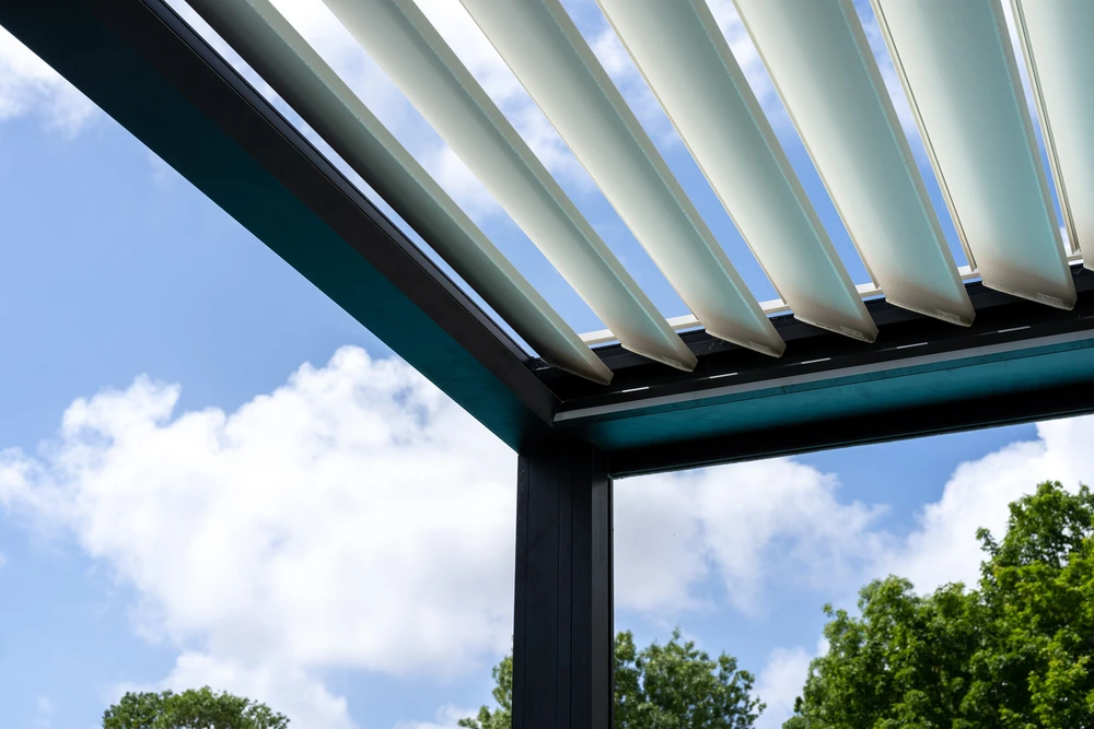 Pergola bioclimatique extérieure avec lames orientables en aluminium blanc partiellement ouvertes