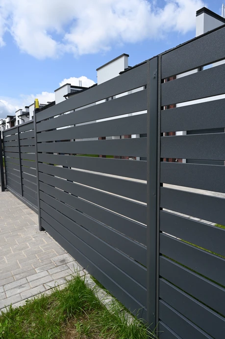 Extérieur résidentiel avec clôture moderne en panneaux métalliques anthracite à lames horizontales ajourées