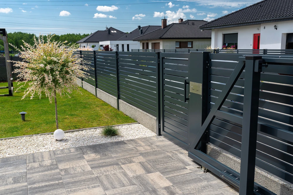 Portail coulissant moderne en aluminium anthracite avec lames horizontales ajourées, intégré dans une clôture assortie