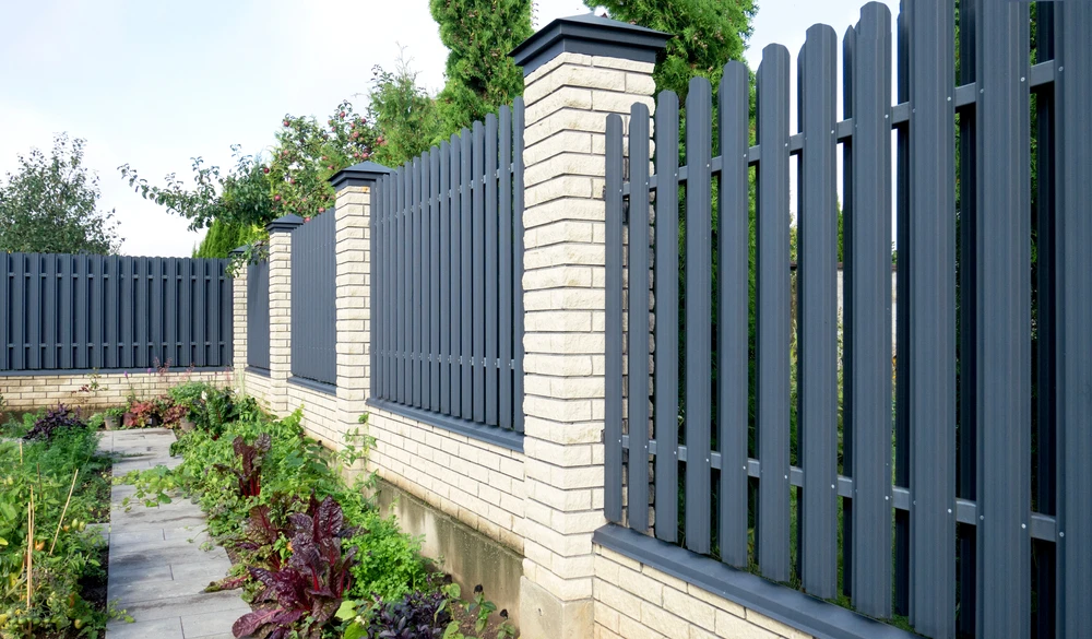 Scène extérieure résidentielle avec clôture moderne le long d'un jardin paysager