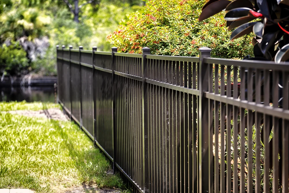 Clôture de jardin résidentiel en aluminium ou PVC de couleur foncée, avec lames verticales à espacement régulier